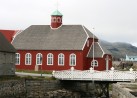 Ein rotes Haus mit weien Fenstern und grauen Dach. Mit einer wei strahlenden Brcke in Vordergrund