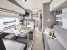 Interior des Wohnmobils aus der Sicht des vorderen Bereiches nach hinten auf die Sitzgruppe, Kche und den Schlafplatz hinten.
