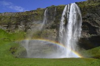 Seljalandsfoss Wasserfall in Sommer mit einem Regenbogen und grnen Gras